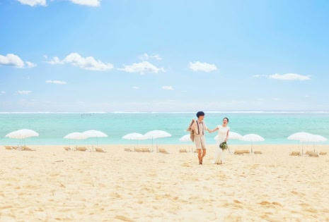 白砂のビーチを歩く新郎新婦と美しい海の風景