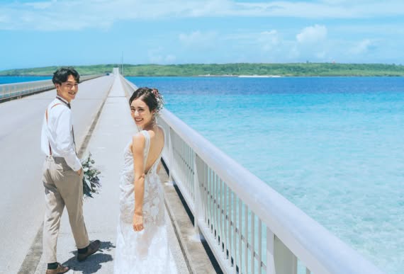 エメラルドグリーンの海に囲まれた橋で撮影する新郎新婦